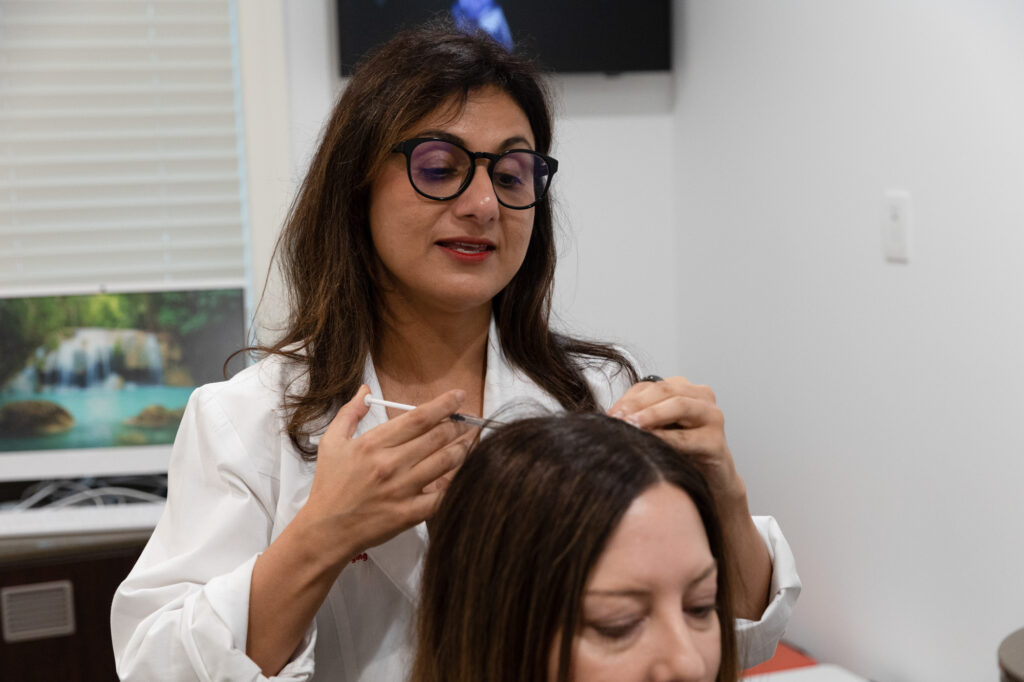 Dr. Meena injects a female patient's scalp with PRP for hair restoration near Northbrook.