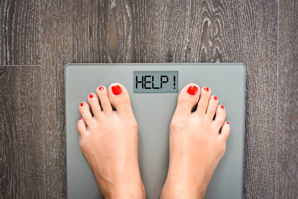 person standing on the scale with HELP spelled on the display